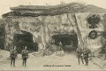 Des soldats brandebourgeois posent devant l'entrée de la carrière souterraine des Cinq Piliers  au fronton de laquelle ils ont sculpté un grand aigle de Brandebourg (peint en rouge) ainsi que la devise "Die guet Brandenburg alle Wege" (Le Brandebourg passe partout). Environs de Noyon dans l'Oise ; photographie de 1915 ou 1916 (France, Première Guerre mondiale). 14-18 
 Art des carrières 
 archives 
 carrière souterraine 
 creutes 
 première guerre mondiale 
 souterrain
tunnels 